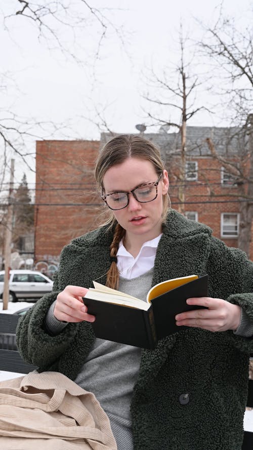 Woman Reading a Book while Sitting on the Bench