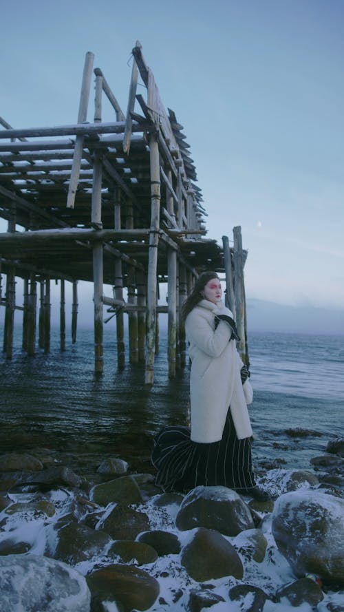 A Woman in Winter Clothing on a Rocky Coast