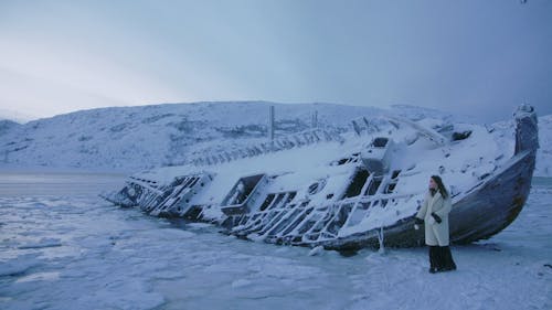 A Woman and a Snow Covered Ship Wreckage