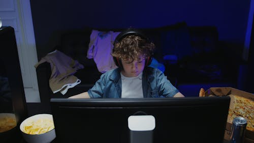 A Child Eating while Playing on a Computer