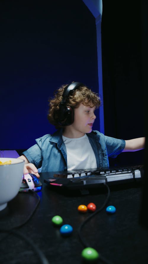 A Child Eating while Playing on a Computer