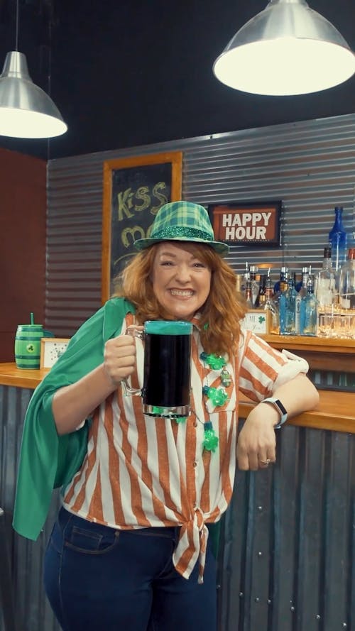 A Woman Holding a Glass of Beer While Looking at the Camera