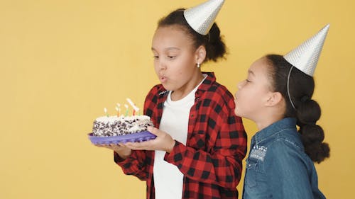 Children Blowing Candles on a Cake