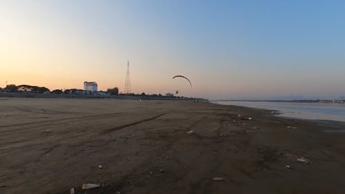 A Person Paragliding by the Shore
