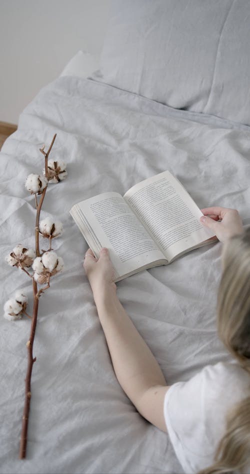 A Woman Reading a Book on Her Bed