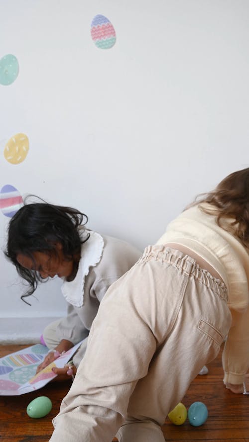 Little Girls Putting up Easter Egg Decorations on the Wall