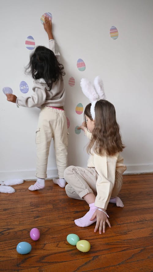 Little Girls Putting up Easter Egg Decorations on the Wall