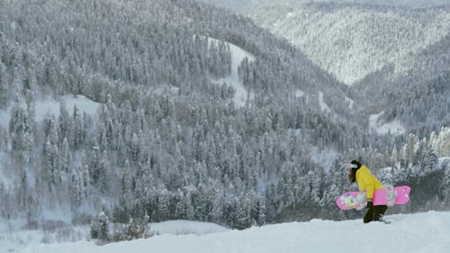 Woman Walking on Snow Carrying Her Snowboard