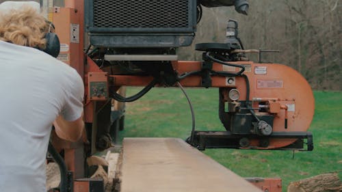 A Worker Cutting a Plank of Wood with a Machine