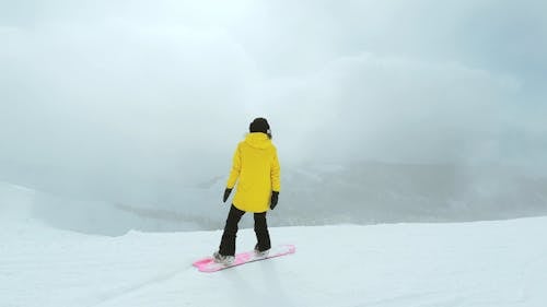 Woman in Yellow Jacket Snowboarding