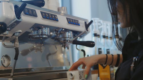 A Woman Pouring Milk and Pumping Caramel on a Glass