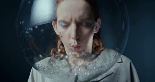 A Woman Blowing Glitters Inside A Bubble Glass