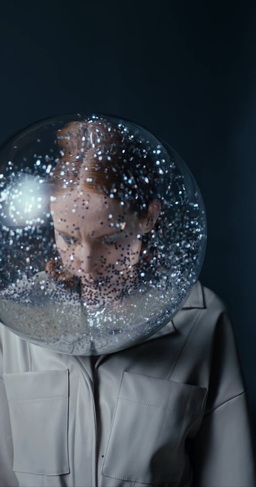 A Woman Blowing Glitters Inside A Bubble Glass