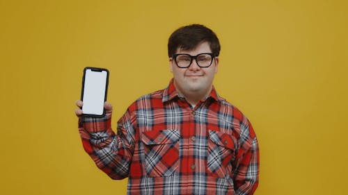 Young Man Holding a Mobile Phone While Poses On Camera