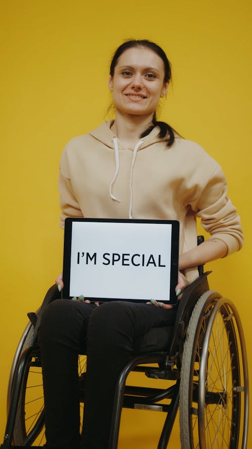 A Woman on a Wheelchair Holding a Tablet that Says I'm Special