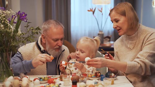 Grand Parents Teaching Their Grand Daughter How to Paint Eggs
