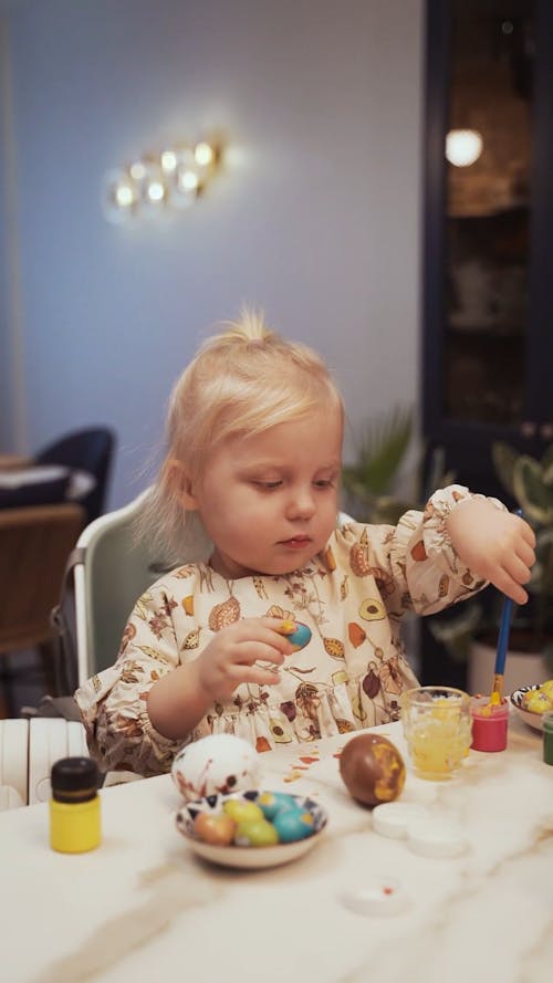 A Kid Painting Eggs on the Table