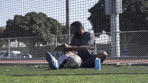 Man Sitting on a Sports Field