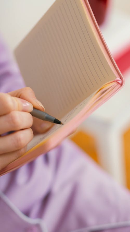 Person Writing on a Notebook