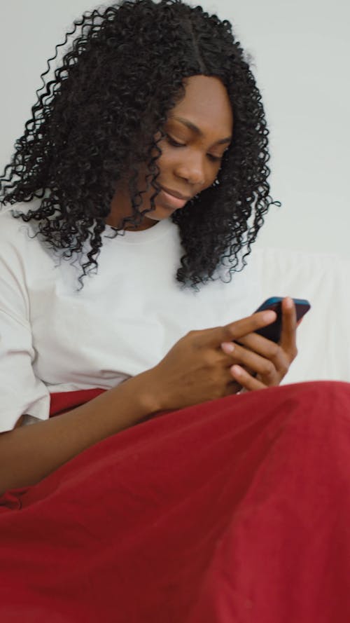 Woman Sitting on Bed Using Cellphone