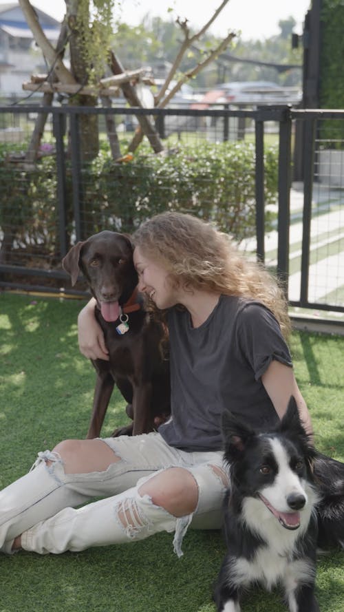 A Woman Petting Her Dogs Outdoors
