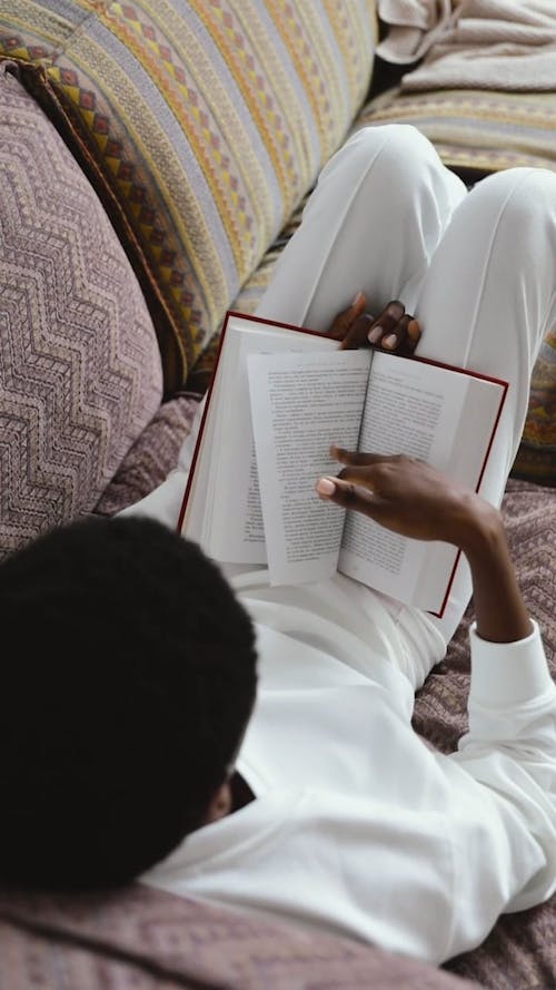 A Person Lying Down on the Sofa while Reading a Book