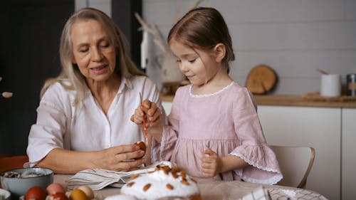 Girl Painting Egg while Grandmother is Teaching her