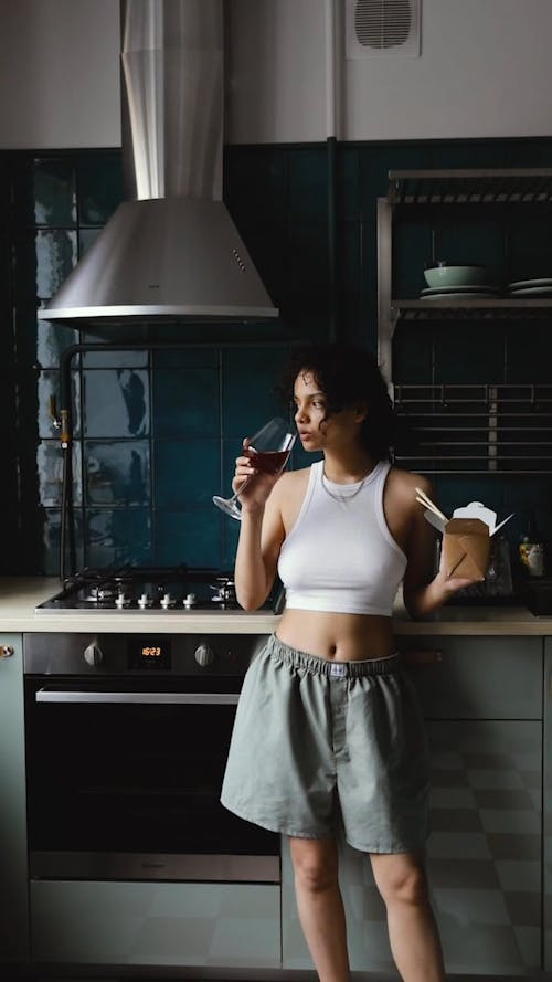 Woman Drinking a Glass of Wine while Holding a Take Out 