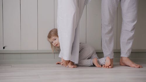 A Toddler Crawling on the Floor While His Parents are Standing