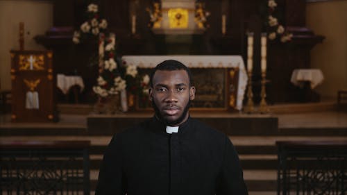 Priest Holding Bible in Front of Altar