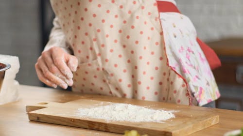 A Woman Putting Flour on a Meat