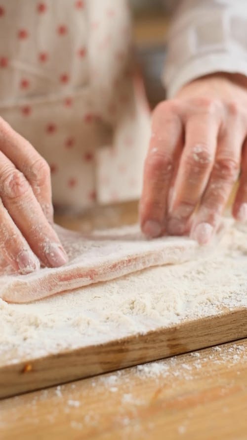 A Woman Coating a Meat with Flour