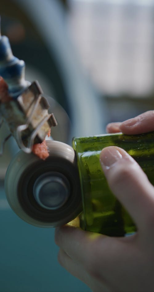 A Person Cutting a Glass Bottle