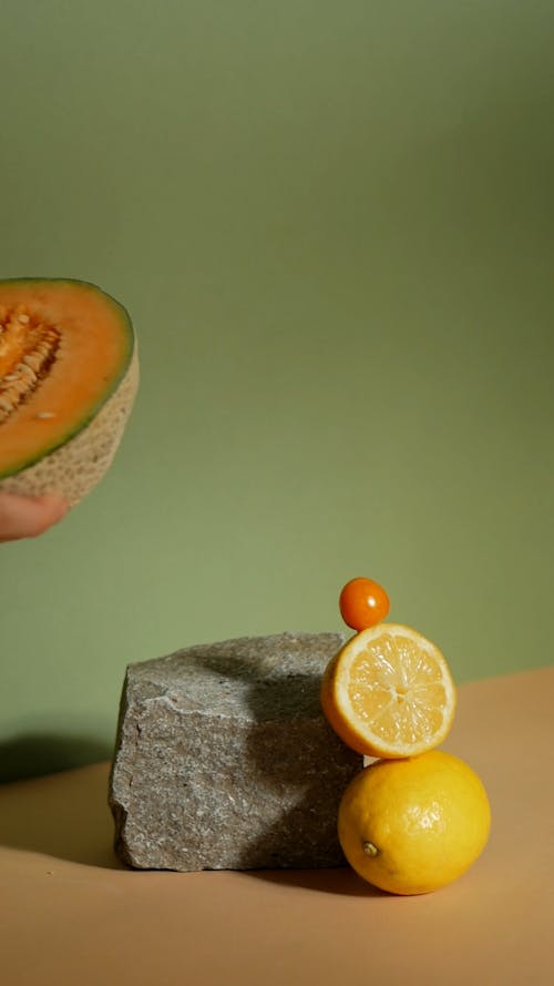 Person Putting Fruits on the Table Beside a Rock