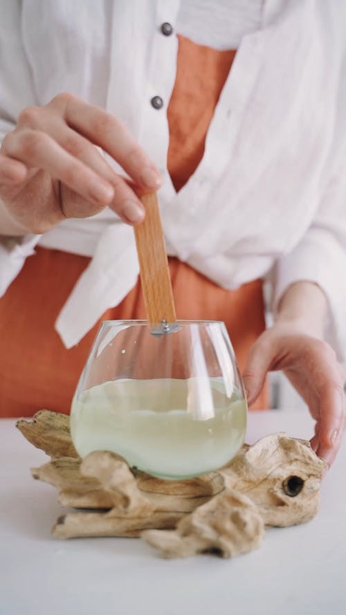 Woman Putting Wooden Wick in Melted Wax 