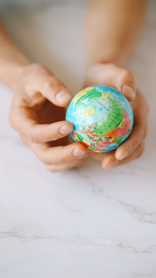 A Person Rotating a Mini Globe