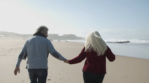 Elderly Couple Enjoying Running on the Beach Sand