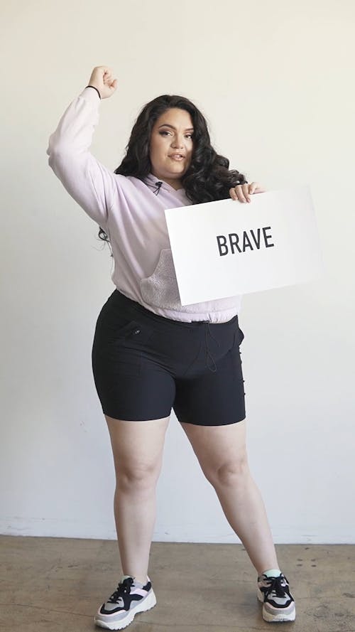 A Plus Size Woman Posing while Holding a Placard
