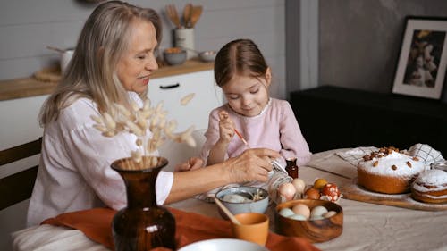 Grandmother and Her Granddaughter Painting Easter Eggs Together