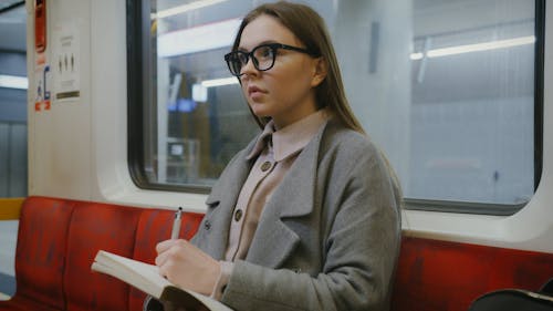 Commuter on Train Taking Notes