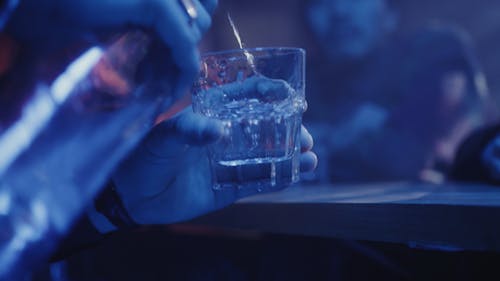 Person Pouring Vodka in a Glass