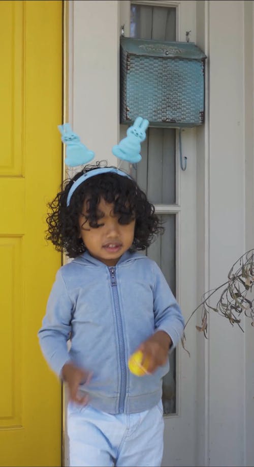 A Girl Putting an Easter Egg inside a Bucket