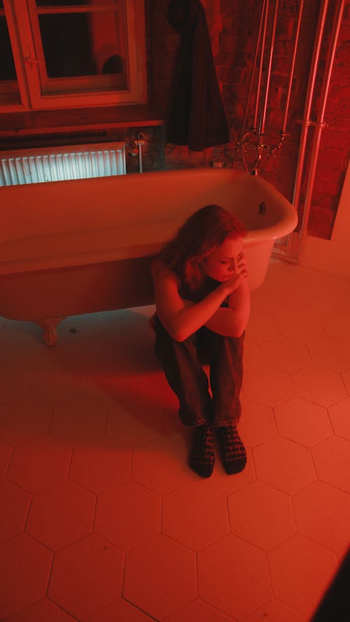 A Depressed Woman Sitting beside a Bath Tub