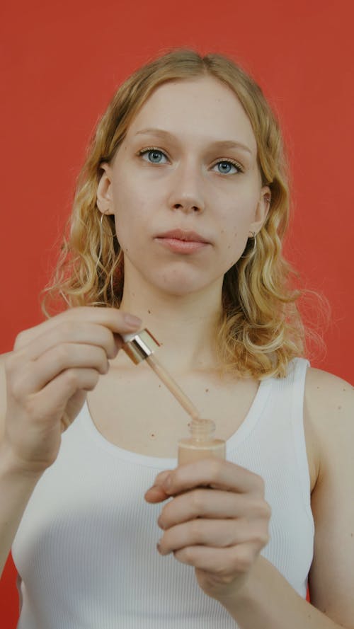 A Woman Dripping Liquid Foundation on Her Face 