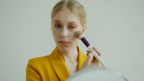 A Woman Applying Make Up  on Her Cheek