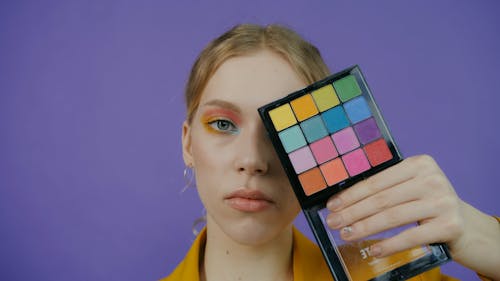 Woman with Eyeshadow Holding Makeup Product