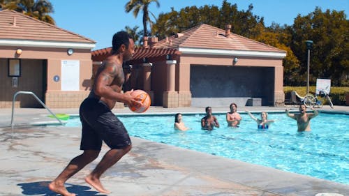 A Man Dunking The Ball In A Pool Floating Basket