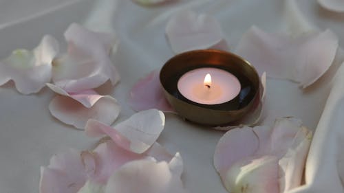 Burning Candle and Rose Petals