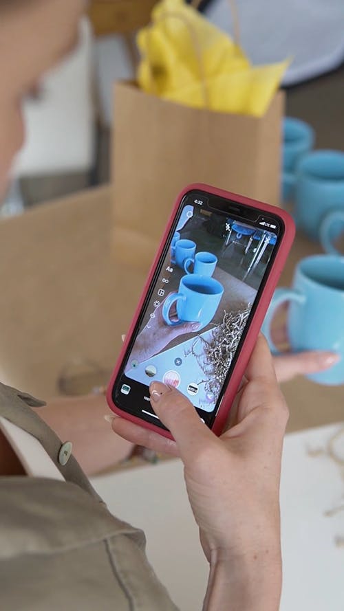 Person Taking Photo of Blue Cups Using a Cellphone