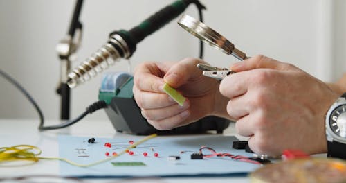 A Electrician is Working using Pliers and Magnifying Glass